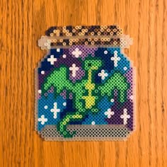 a cross stitch coaster with a cactus on it's side, sitting on a wooden surface