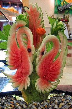 two flamingos made out of watermelon are sitting on a table