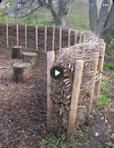 a pile of wood sitting in the middle of a forest next to a wooden fence