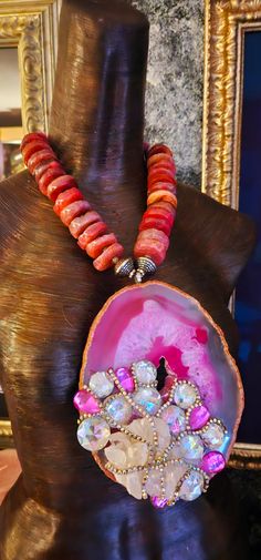 After a re-stringing repair, this piece is now ready for a new home! A 7" x 5" hot pink and Fuchsia Brazilian agate hosts a rough white quartz cluster, faux clear and pink crystals and rows of silver aurora borealis rhinestones! The pendant is suspended from an agate rondelle statement necklace which measures 21". The reddish-pink agates are polished on one side and rough on the other. Each agate is spaced with an ornate silver tone metal bead. Flanking the pendant are rhinestone rondelles and silver tone stamped tribal bi-cone beads. The back is finished with more tribal beads, rhinestone rondelles, frosted pink druzy agates and clear faceted crystals. Closes with a fancy silver tone hook and eye. This is a very dense and heavy piece so please know your tolerance before you buy. From the Artisan Pink Jewelry With Round Beads, Coral Gemstone Jewelry For Weddings, Pink Ruby Necklace For Party, Red Artisan Jewelry For Wedding, Artisan Red Jewelry For Wedding, Red Handmade Jewelry For Wedding, Pink Agate Gemstone Bead Necklace, Pink Agate Beaded Necklaces As Gift, Unique Pink Gemstone Beads Jewelry