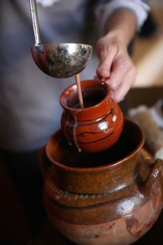 a person pouring water into a clay pot