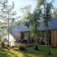 a small house with a hot tub in the yard next to trees and grass, on a sunny day