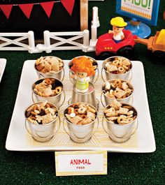 small tins filled with food sitting on top of a white plate next to toy cars