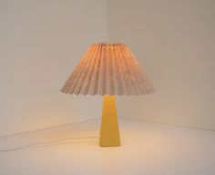 a yellow table lamp sitting on top of a white floor next to a light bulb