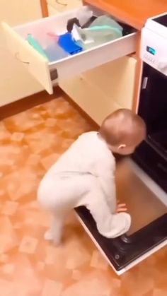 a baby standing in front of an open oven