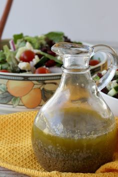 a glass pitcher filled with green liquid next to a bowl of salad on a yellow towel