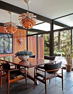 an old photo of a dining room table and chairs in front of a wooden paneled wall