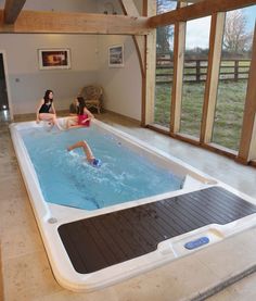 two women sitting in an indoor hot tub with sliding glass doors on the wall and floor