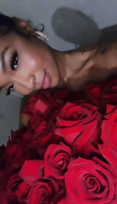 a beautiful woman laying on top of a bed of red roses