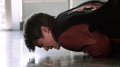 a man in black shirt and red jacket laying on the floor with his head down