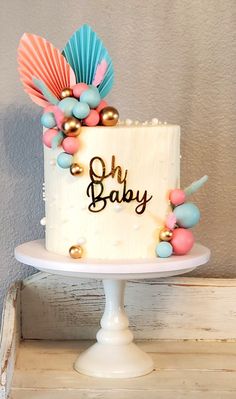 a white cake with pink, blue and gold decorations on it that says oh baby