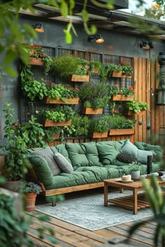 an outdoor living area with green couches and potted plants on the wall behind it