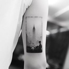 a man with a bicycle in front of a cityscape tattoo on his arm