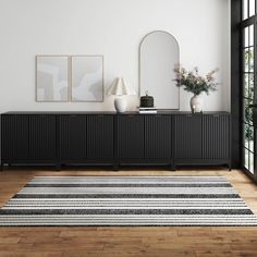 a black and white striped rug in front of a dresser with two vases on it