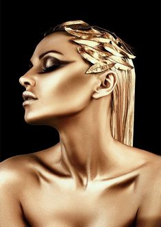 a woman's face with gold leaves on her head and hair in the wind