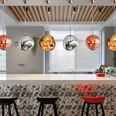 the modern kitchen has three hanging lights above the bar and four stools in front of it