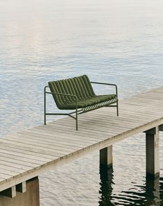 a green chair sitting on top of a wooden pier