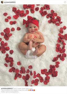 a baby with red paint on it's face sitting in a circle of petals