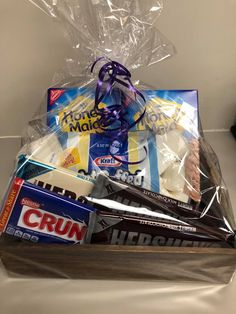 a basket filled with toothbrushes, cookies and other items in plastic wrap on top of a counter