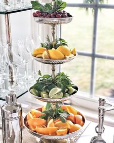 three tiered trays filled with fruit and vegetables on a table next to wine glasses