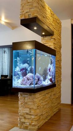 a fish tank sitting on top of a wooden floor next to a stone wall in a living room