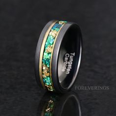 a wedding ring with green and gold inlays