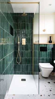 a green tiled bathroom with a toilet and shower