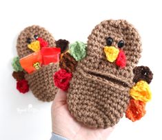 a hand holding two small crocheted turkeys