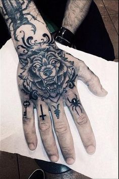 a man's hand with a wolf and cross tattoo on the middle of it