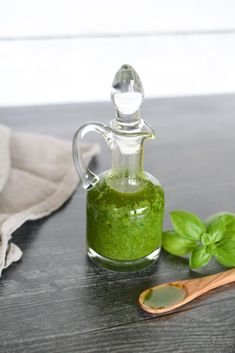 basil oil in a glass bottle next to a wooden spoon