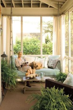 a woman sitting on a porch reading a book with a dog laying next to her