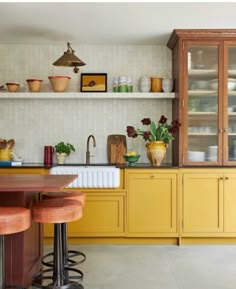 a kitchen with yellow cabinets and stools