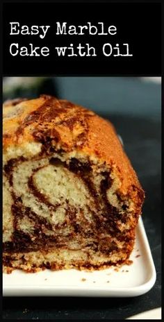 an easy marble cake with oil is cut in half on a white plate and sits on a black surface