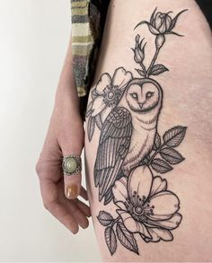 a woman's thigh with an owl and flowers tattoo on it