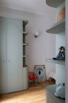 a teddy bear sitting on top of a shelf next to a red chair in a room