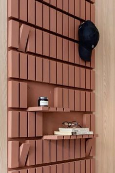 a shelf that has some books on it and a hat hanging from the wall behind it