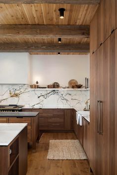 a kitchen with wooden cabinets and marble counter tops, along with an area rug on the floor