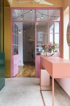 the inside of a pink and yellow room with lots of windows