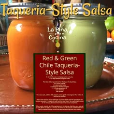 red and green chili sauce in a glass jar on a tray with limes behind it