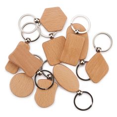 wooden keychains with metal rings and wood tags on them are laid out in a pile