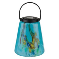 a blue glass tea light holder with a black handle and colorful swirls on it