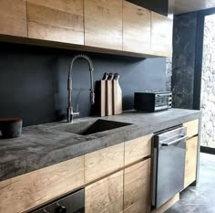 a modern kitchen with black walls and wooden cabinets, stainless steel dishwasher on the counter