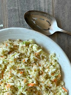 a white bowl filled with coleslaw and carrots on top of a wooden table