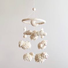 a mobile with sheeps hanging from it's sides in front of a white wall