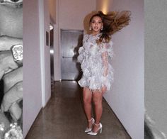 a woman standing in a hallway with her hair blowing in the wind and wearing high heels