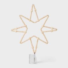 a wooden beaded star ornament hanging from a string on a white background