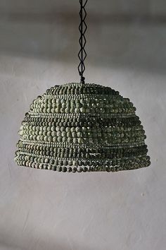 a green beaded light hanging from a ceiling