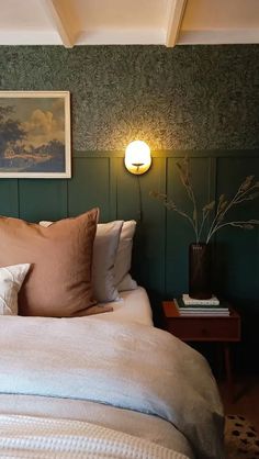 a bed with two pillows and some pictures on the wall above it in a bedroom