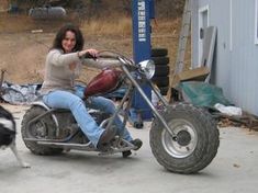 a woman riding on the back of a motorcycle next to a black and white dog