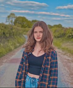 a woman standing in the middle of a dirt road